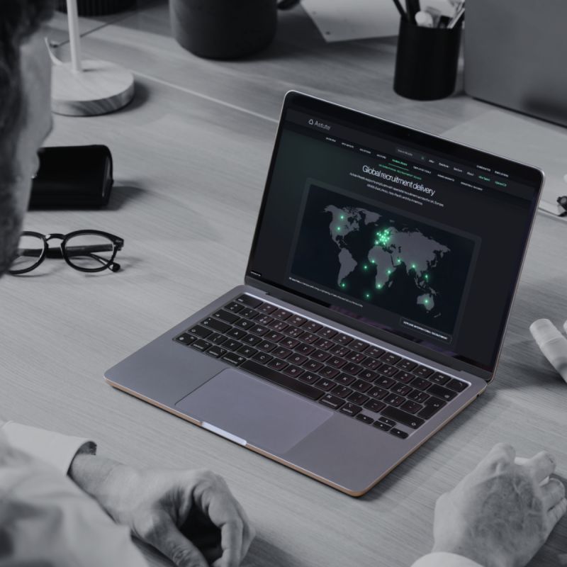 Post photo: a laptop on a desk showing the job platform's global recruitment delivery page, a world map dotted with live locations